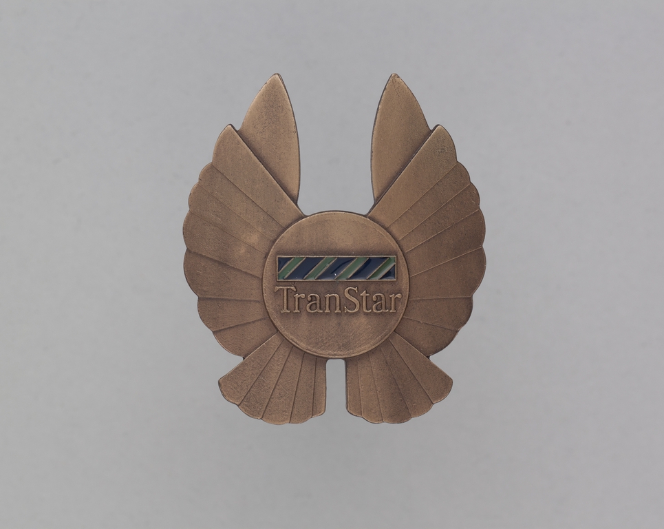 Objects | flight officer cap badge: TranStar Airlines | SFO Museum