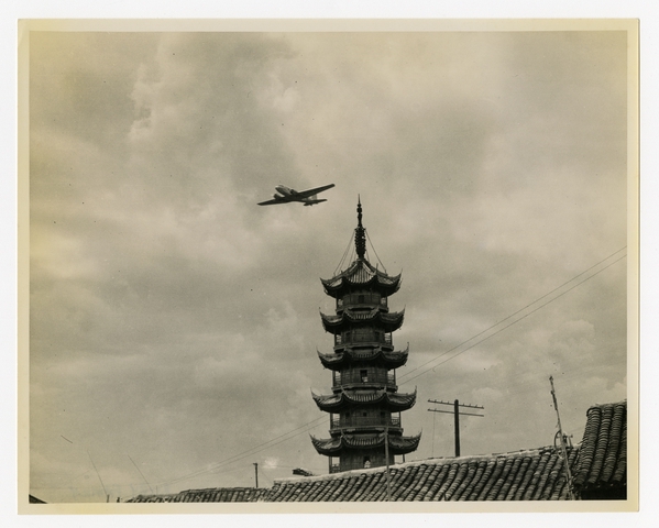 Photograph: aircraft (Douglas DC-2 in flight over pagoda